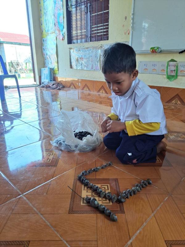 3 A boy use the cover of snail to write the first Khmer consonant, Ko.jpg
